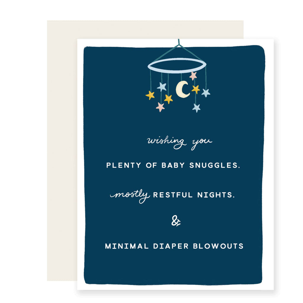 Greeting card with dark blue background and image of a mobile hanging from top of card with yellow moon and pastel stars. White text says, "wishing you plenty of baby snuggles. mostly restful nights. & minimal diaper blowouts". White envelope included.
