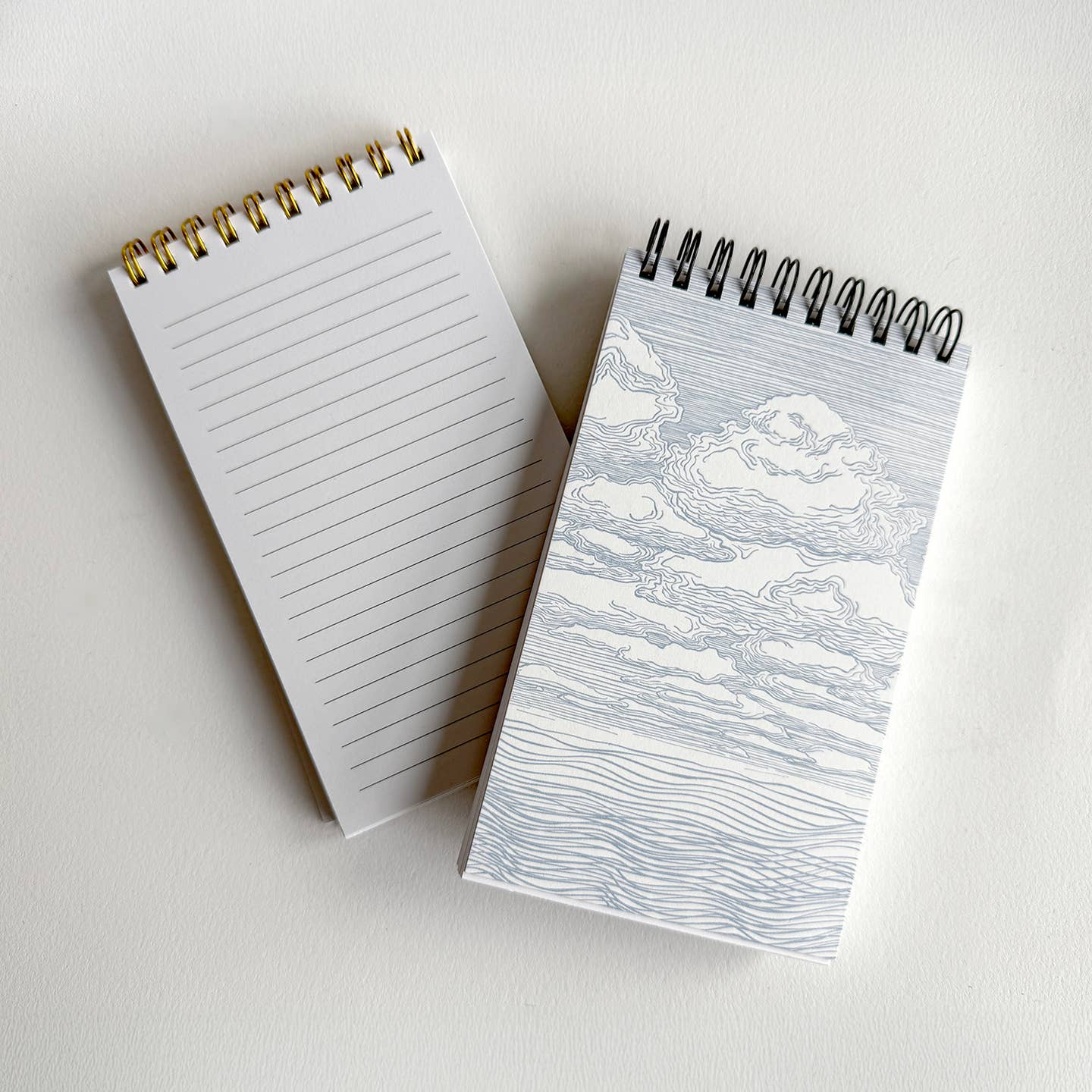 Notebook with ruled lines and cover with black and white clouds drawing on cover.