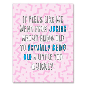 Greeting card with pink background with dark pink squiggles. White text says, "It feels like we went from joking about being old to actually being old a little too quickly." Envelope included. 