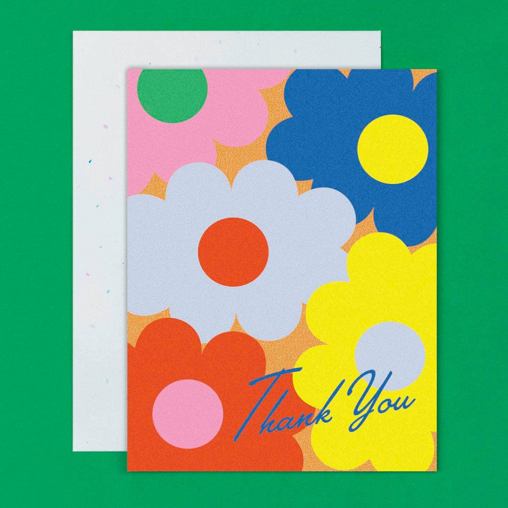 Greeting  card with background images of large flowers in pink, blue, yellow and red with blue text says, "Thank you". Envelope included.