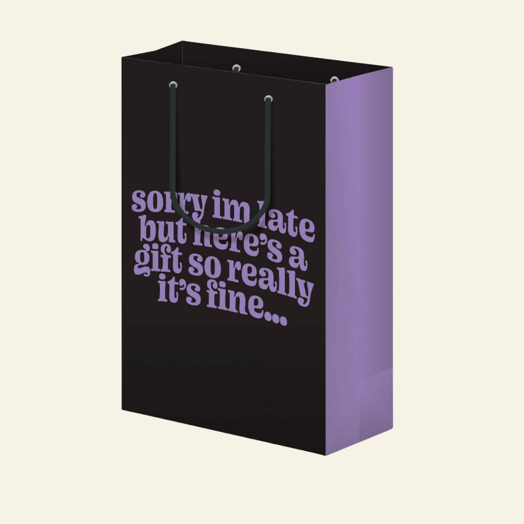 Black background with purple text says, "Sorry I'm late but here's a gift so really it's fine...". Black cord handle. 