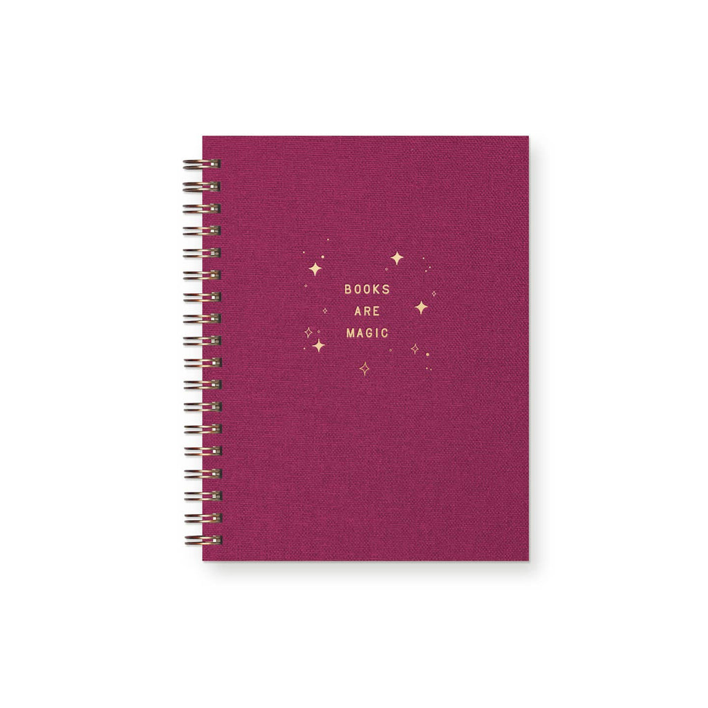 Notebook cover in dark rose with gold foil text says, "Books are magic" and star bursts. Gold coil binding.