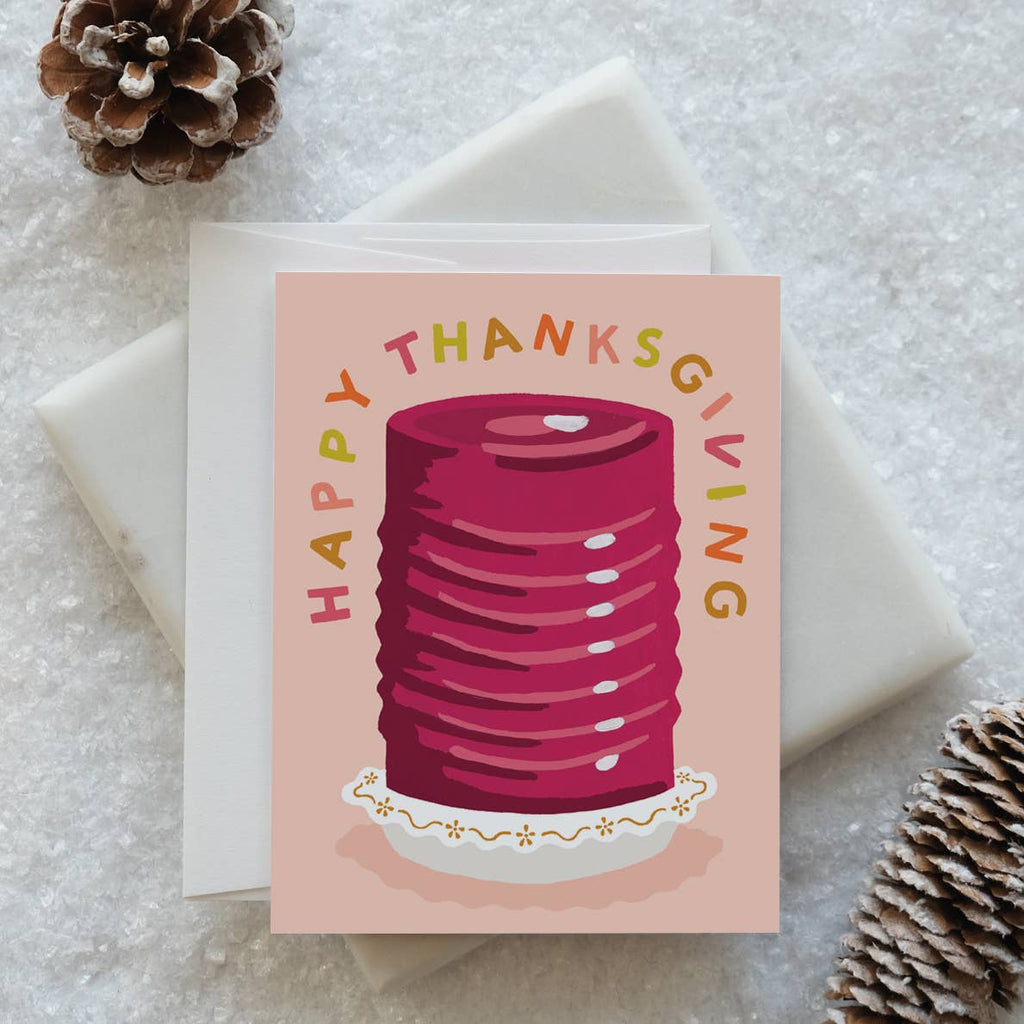 Greeting card with pink background and image of cranberry jelly from the can on a small place. Text says, "Happy Thanksgiving". Envelope included.