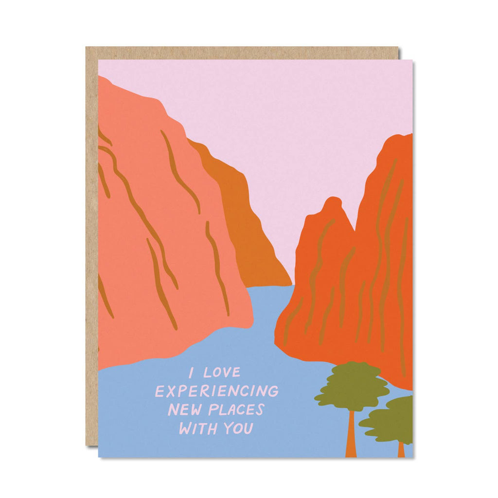 Image of two mountains with blue river and pink sky and two trees. Pink text says, "I love experiencing new places with you". Kraft envelope is included. 