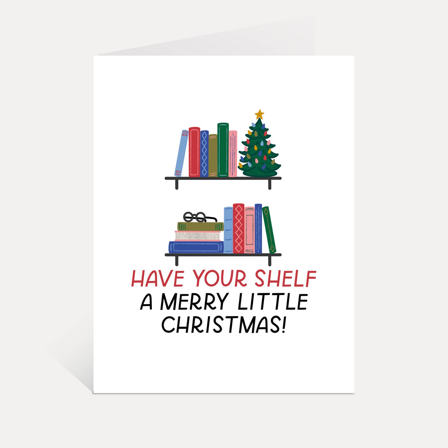 Greeting card with white background and image of books on shelves with Christmas tree. Red and black text says, "Have your shelf a merry little Christmas!". Envelope included.