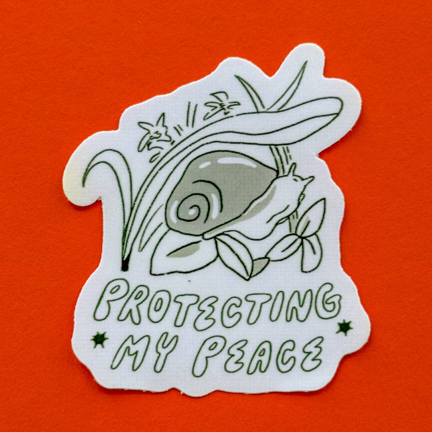 Decorative sticker with image of a snail hiding under grass with black and white text says, "Protecting my peace".