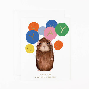 Greeting card with white background and image of a brown guinea pig holding a bunch of balloons with gold foil text says, "YAY" and "Oh, we're guinea celebrate!". Envelope included. 