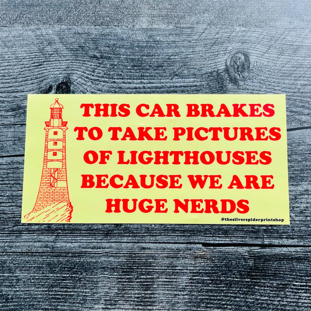 Decorative sticker with yellow background and image of a lighthouse with red text says, "This car brakes to take pictures of lighthouses because we are huge nerds". 