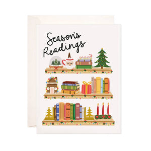 White background with image of shelves with books, Christimas tree, candles and gingerbread house with black text says, “Season’s readings”. White envelope is included.          