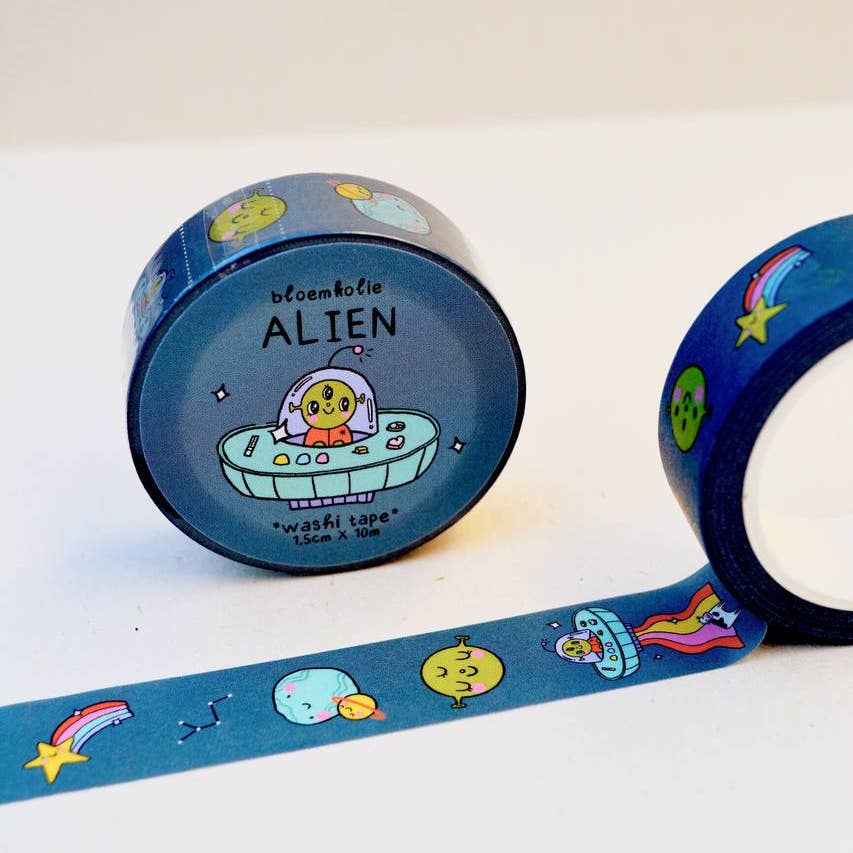 Image of roll of washi tape with dark blue background and images of aliens, spaceships, planets and stars. 