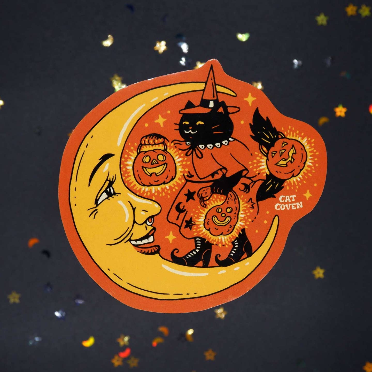 Decorative sticker with orange background and image of a yellow moon and a black cat wearing a witch's costome holding Jack O'latern.