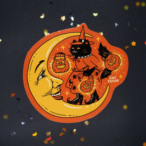 Decorative sticker with orange background and image of a yellow moon and a black cat wearing a witch's costome holding Jack O'latern.