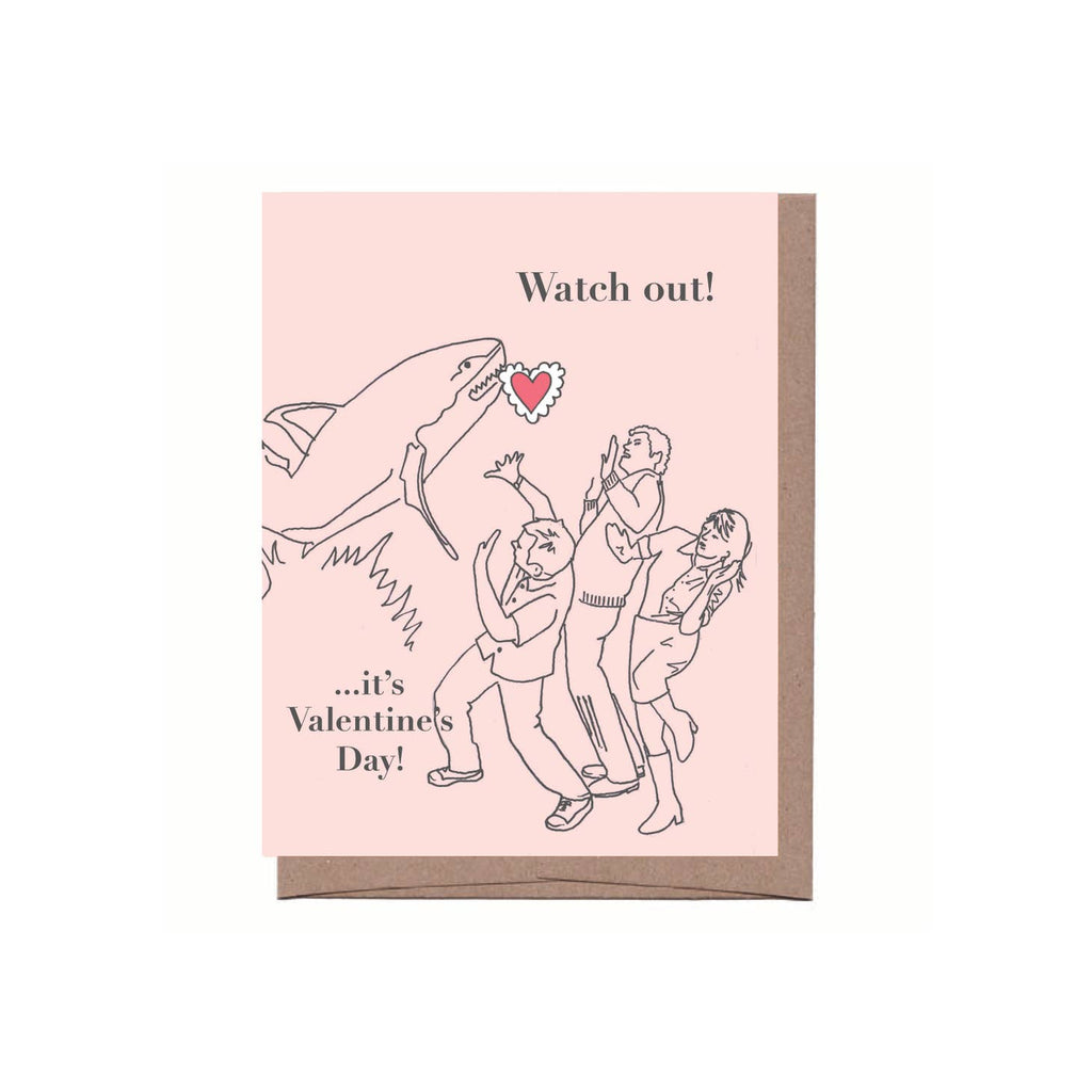 Greeting card depicting a shark holding a heart in its mouth jumping out at 3 people. Text says "Watch out! It's Valentine's Day!"