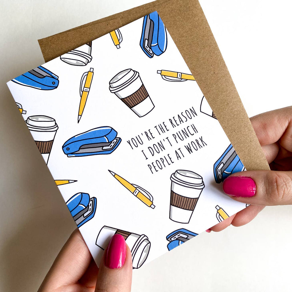 White card with blue staple, yellow pens and coffee cups. Text says "You're the reason I don't punch people at work"