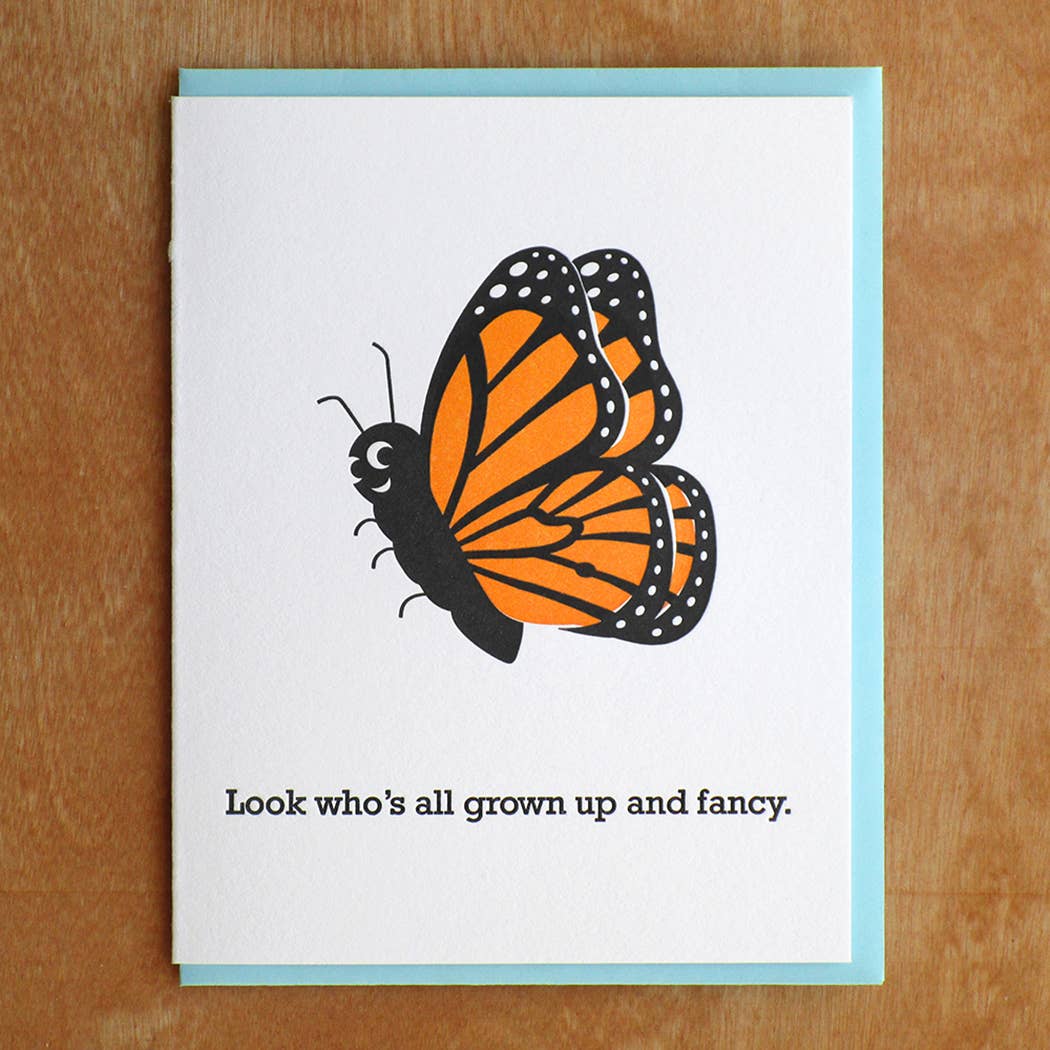 Greeting card with white background and image of a black and red monarch butterfly with black text says, "Look who's all grown up and fancy.". Light blue envelope included,