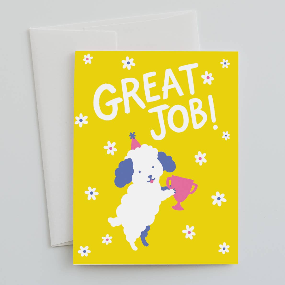 Greeting card with yellow background with white flowers and image of a white dog with blue ears and a pink party hat holding a pink trophy cup. White text says, "Great job!". White envelope included. 