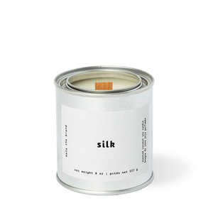 Image of candle with white label and white text says, "Silk". 