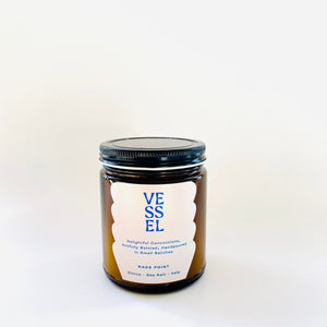 Image of brown glass jar with black lid and ivory label with blue text says, “Vessel” and “Race Point”. 
