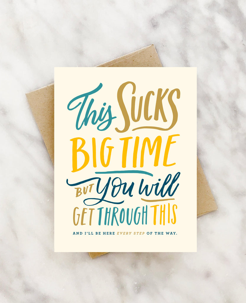 Ivory card with multi colored text saying, “This Sucks Big Time But You Will Get Through This And I’ll Be There Every Step of the Way”. A brown envelope is included.