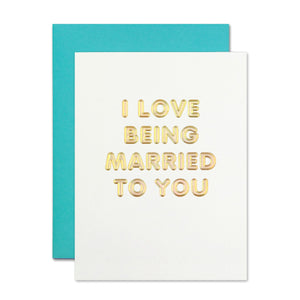 Ivory card with gold foil bubble text saying, “I Love Being Married To You”. A teal envelope is included.