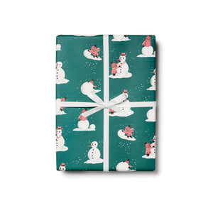 Image of a wrapped package with green background with images of child making a snowman in pink, white and black. 