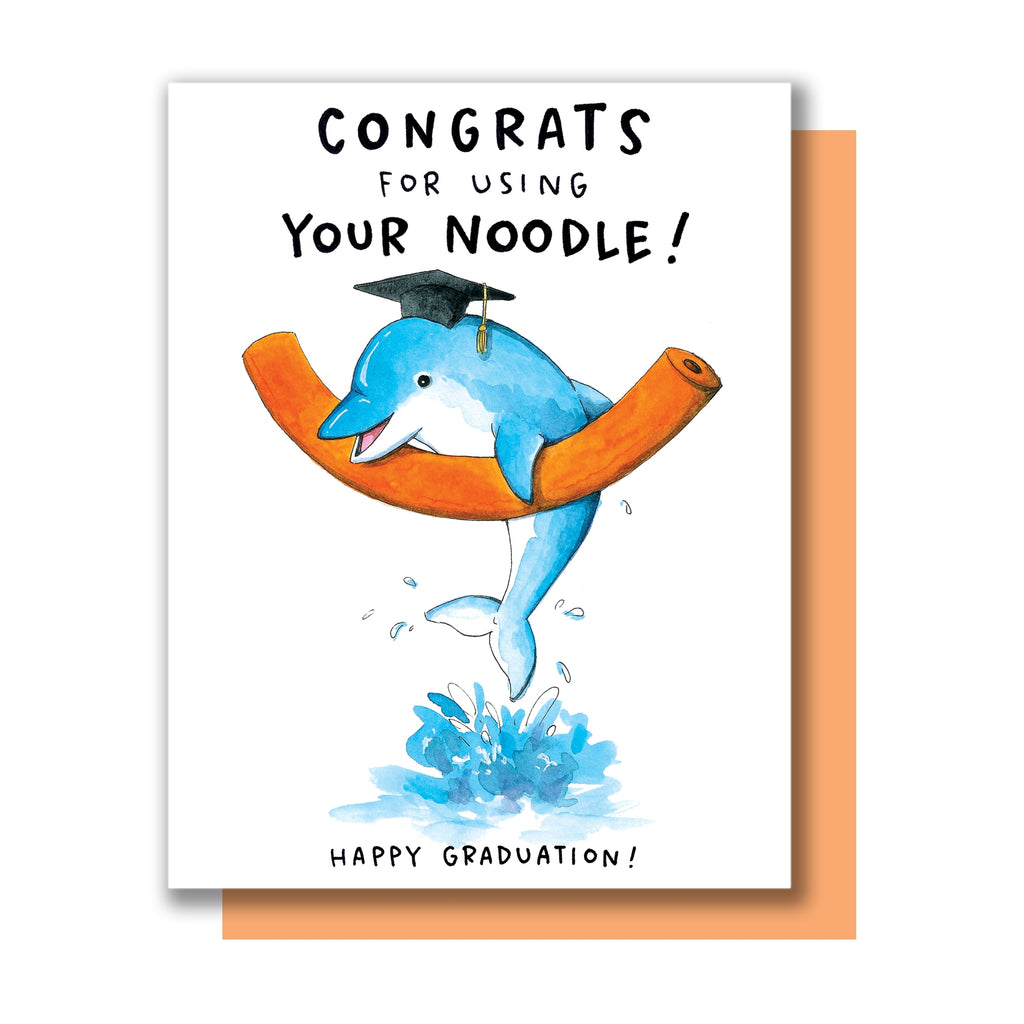 White card with black text saying, “Congrats for Using Your Noodle! Happy Graduation!”  Image of a blue dolphin wearing a black graduation hat and holding onto an orange pool noodle in the water. A peach envelope is included.