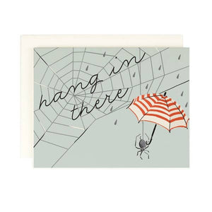 Grey background with image of a dark grey spider holding a red and white stripe umbrella. Image of a spider web in dark grey with black text says, “Hang in there”.  A white envelope is included.       