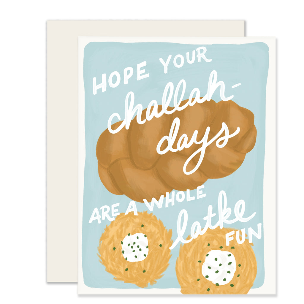 White card with blue inset background with white text saying, “Hope Your Challah-Days Are A Whole Latke Fun”. Images of a loaf of challah bread and two latke pancakes with sour cream and chives. A white envelope is included.