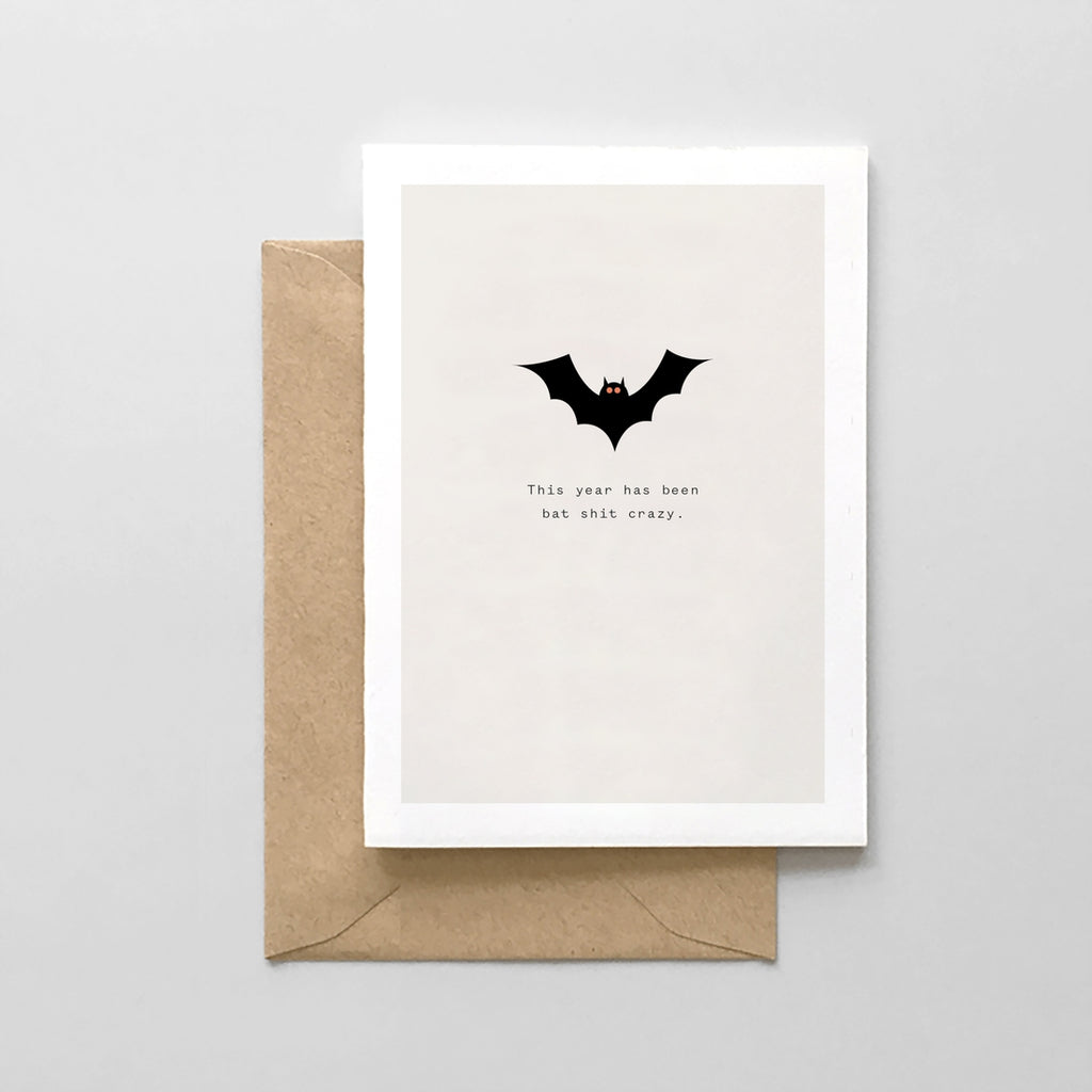 White card with gray background with black text saying, "This Year Has Been Bat Shit Crazy". Image of a black bat. A brown envelope is included.