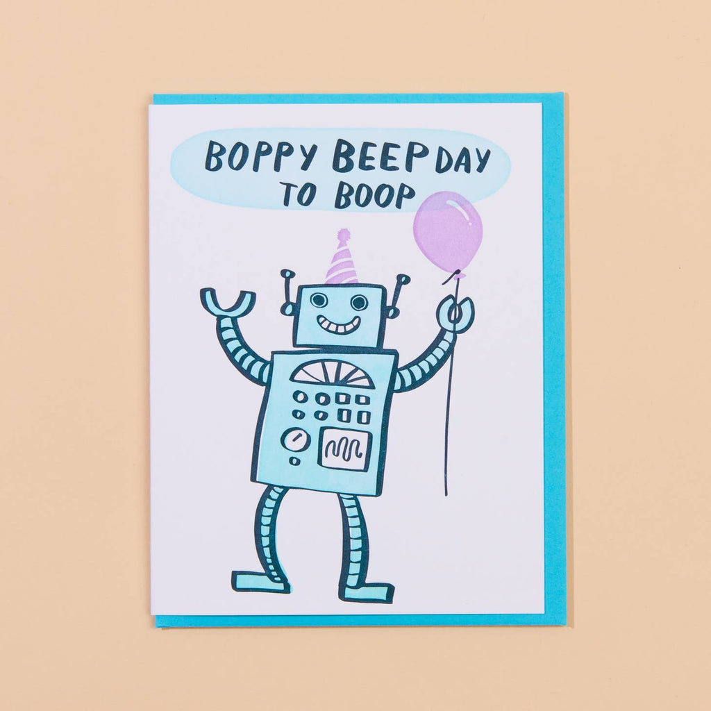 White card with image of a light blue robot with a lavender balloon and party hat. Blue text says “Boppy Beep Day to Boop”. Blue envelope is included.  