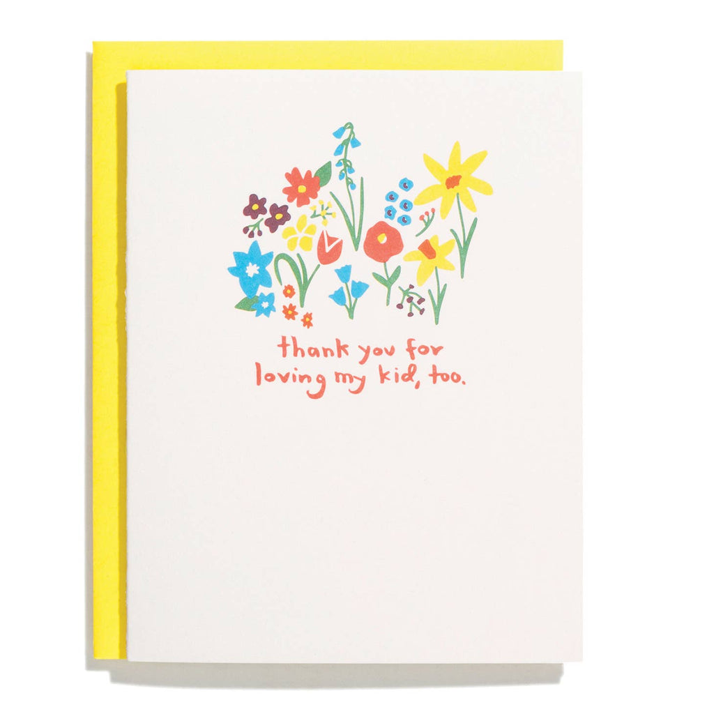 White card with orange text saying, “Thank You for Loving My Kid, Too”. Images of various colored flowers in a garden about the text. A yellow envelope is included.
