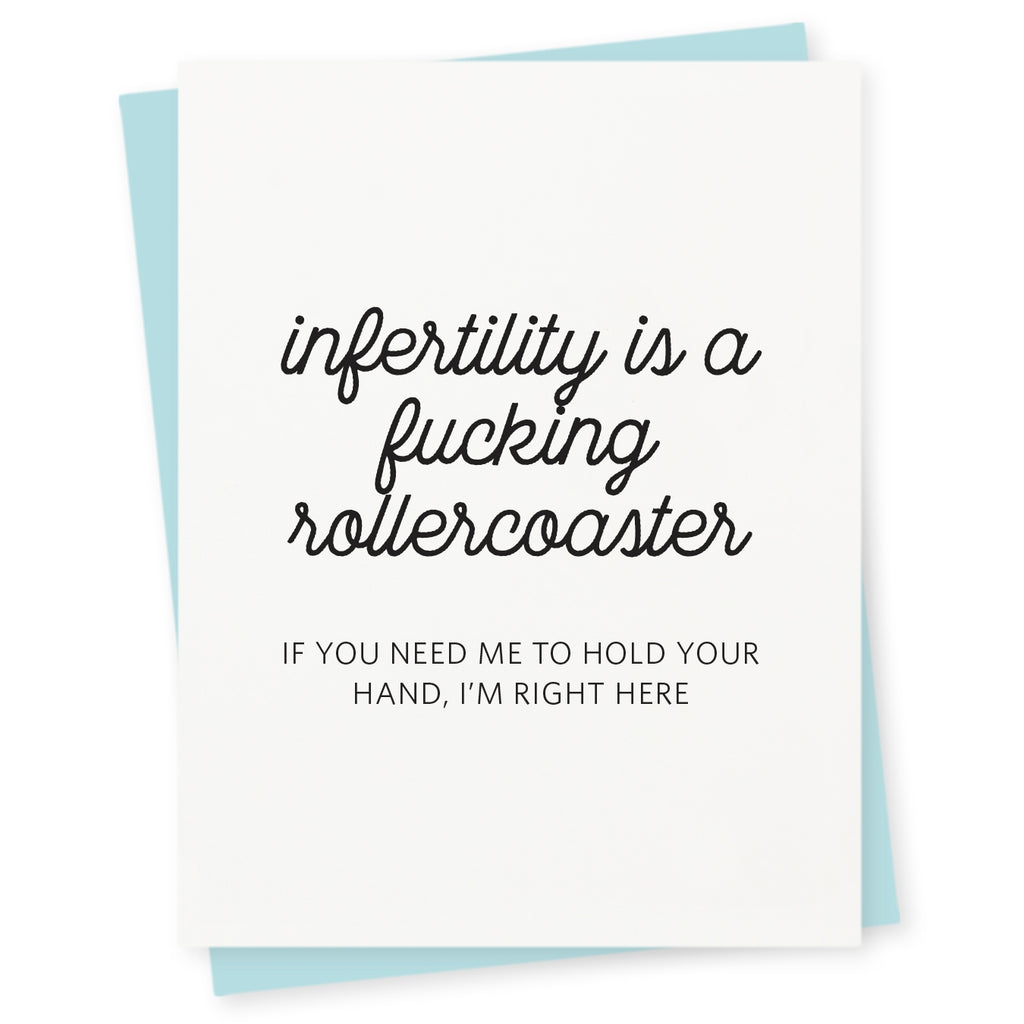 White card with black text saying, “Infertility is a Fucking Rollercoaster If You Need Me to Hold Your Hand, I’m Right Here”.  A light blue envelope is included.