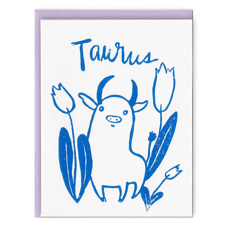 Ivory card with blue text saying, “Taurus”. Images of the bull Taurus zodiac sign. A purple envelope is included.
