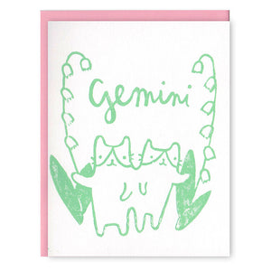 Ivory card with green text saying, “Gemini”. Image of the set of twins (cats) Gemini zodiac sign. A pink envelope is included.