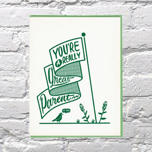 Ivory card with green text saying, “You’re A Really Great Parent It’s True”. Image of a ribbon flag with green flowers and a green bird. A green envelope is included.