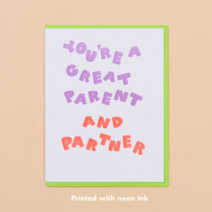 White card with neon lavender text that says “You’re a great parent” and  neon orange text that says “and partner”. Neon green envelope included.          