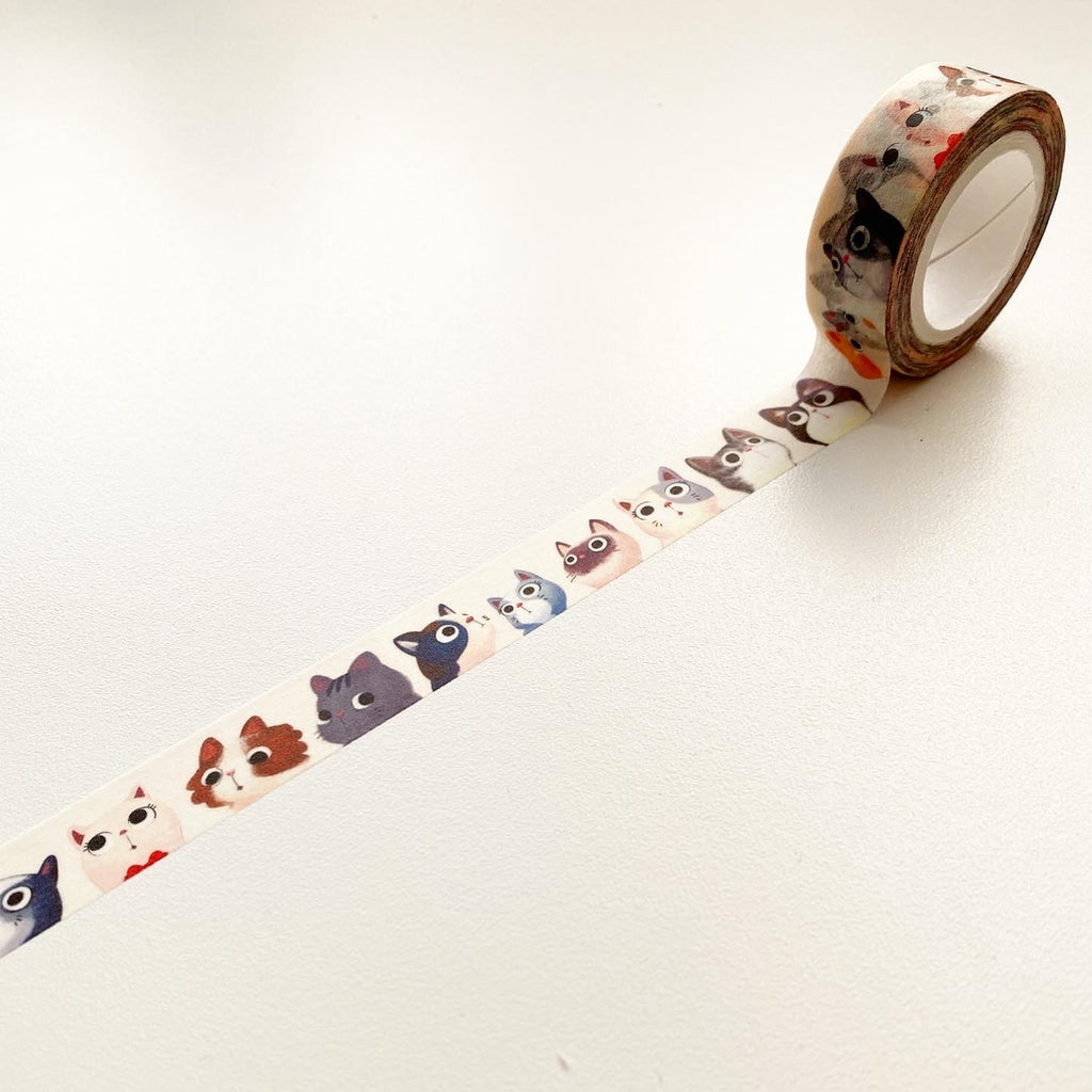 Ivory tape with various cats faces in a repeating pattern. Cat faces include a black cat, gray cat, white cat and white with brown cat.