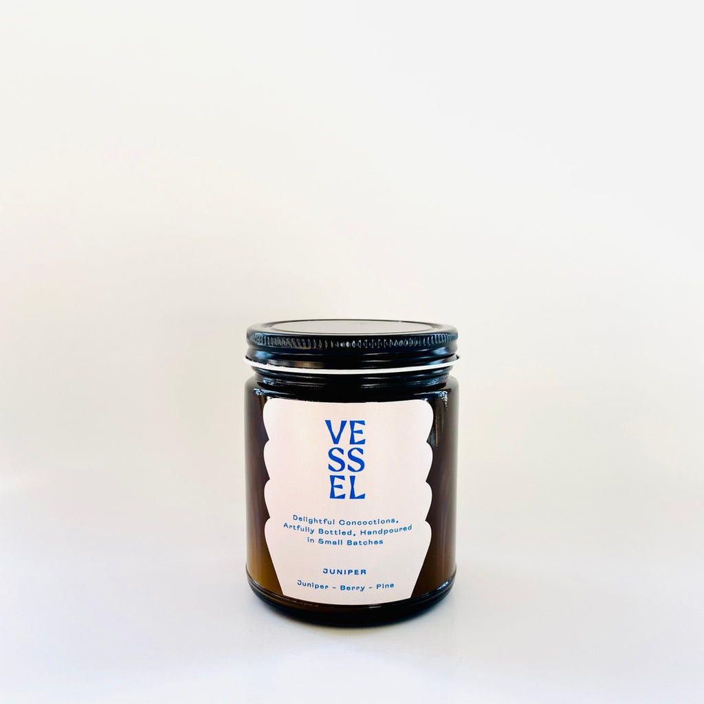Image of brown glass jar with black lid and ivory label with blue text says, “Vessel” and “Juniper”. 
