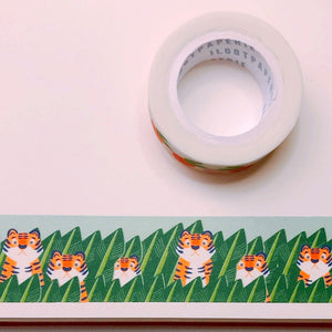 Decorative tape with blue sky background with images of orange tigers peeking out of green bushes.