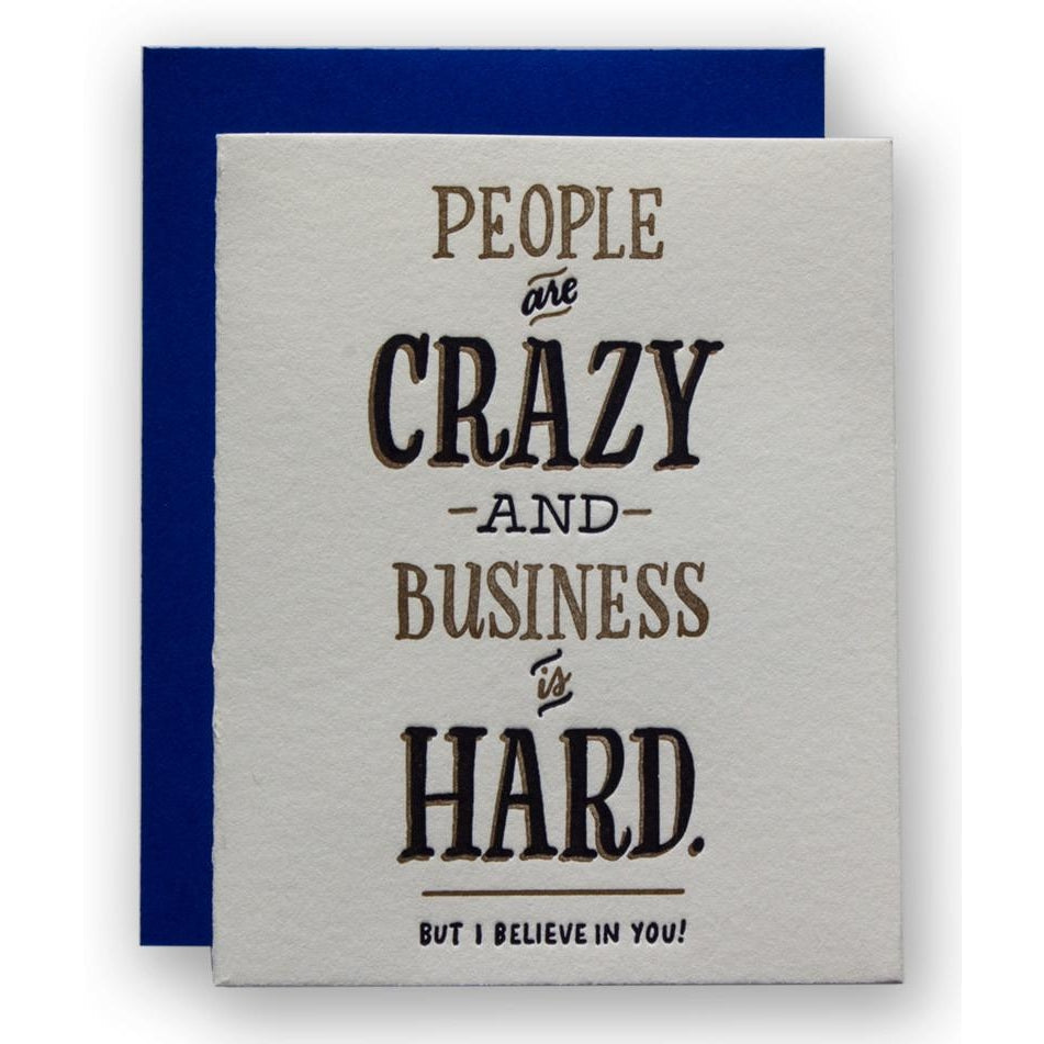 White card with black and gold foil text saying, "People Are Crazy and Business is Hard. But I believe in You!"  A blue envelope is included.