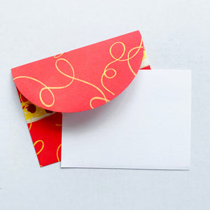 White notecard with red envelope with image of yellow spaghetti and meatballs on a plate. 