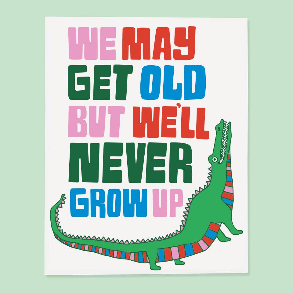 White background with image of a green alligator with a striped underbelly in red, pink, blue and green. Multicolored text  says, “We may get old but we’ll never grow up”. An envelope is included.     