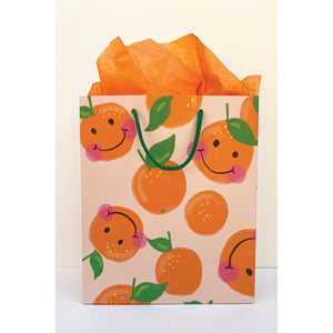 Image of gift bag with pale peach background and images of oranges with smiley faces and green leaves and stem. Green cord handle. 