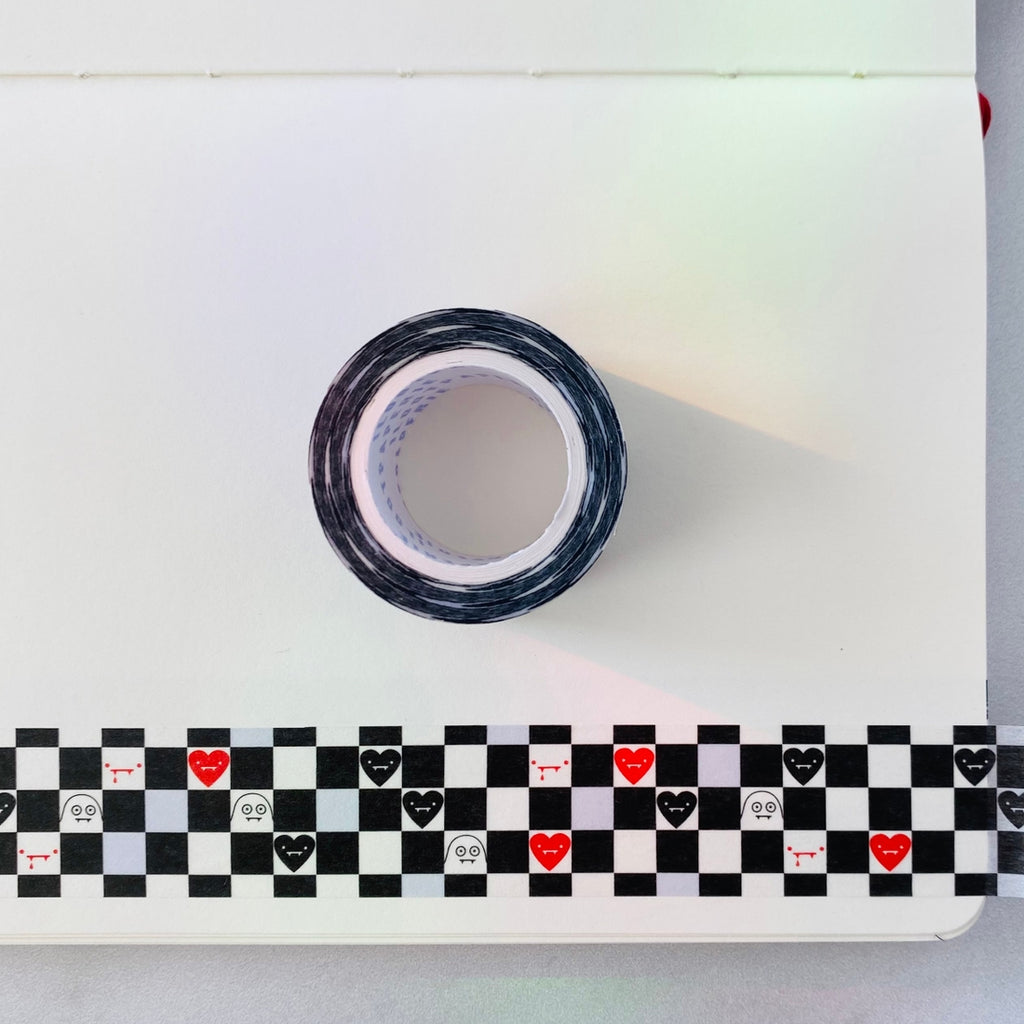 Decorative tape with black and white checkerboard background. Images of black hearts, red hearts, white ghosts and dripping red blood in board squares.