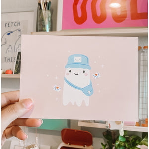 Image of a small white ghost wearing a light blue postal hat and mail bag holding an envelope with a pink heart on it.             