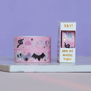 Decorative tape with pink background with images of pink moons, white ghosts, white skulls, black bats and pink mushrooms with gold foil stars.