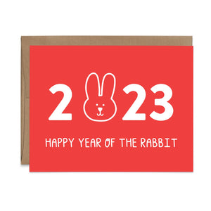 Red card with white text saying, "2023 Happy Year of the Rabbit". Image of a rabbit head replacing the zero in 2023. A brown envelope is included.
