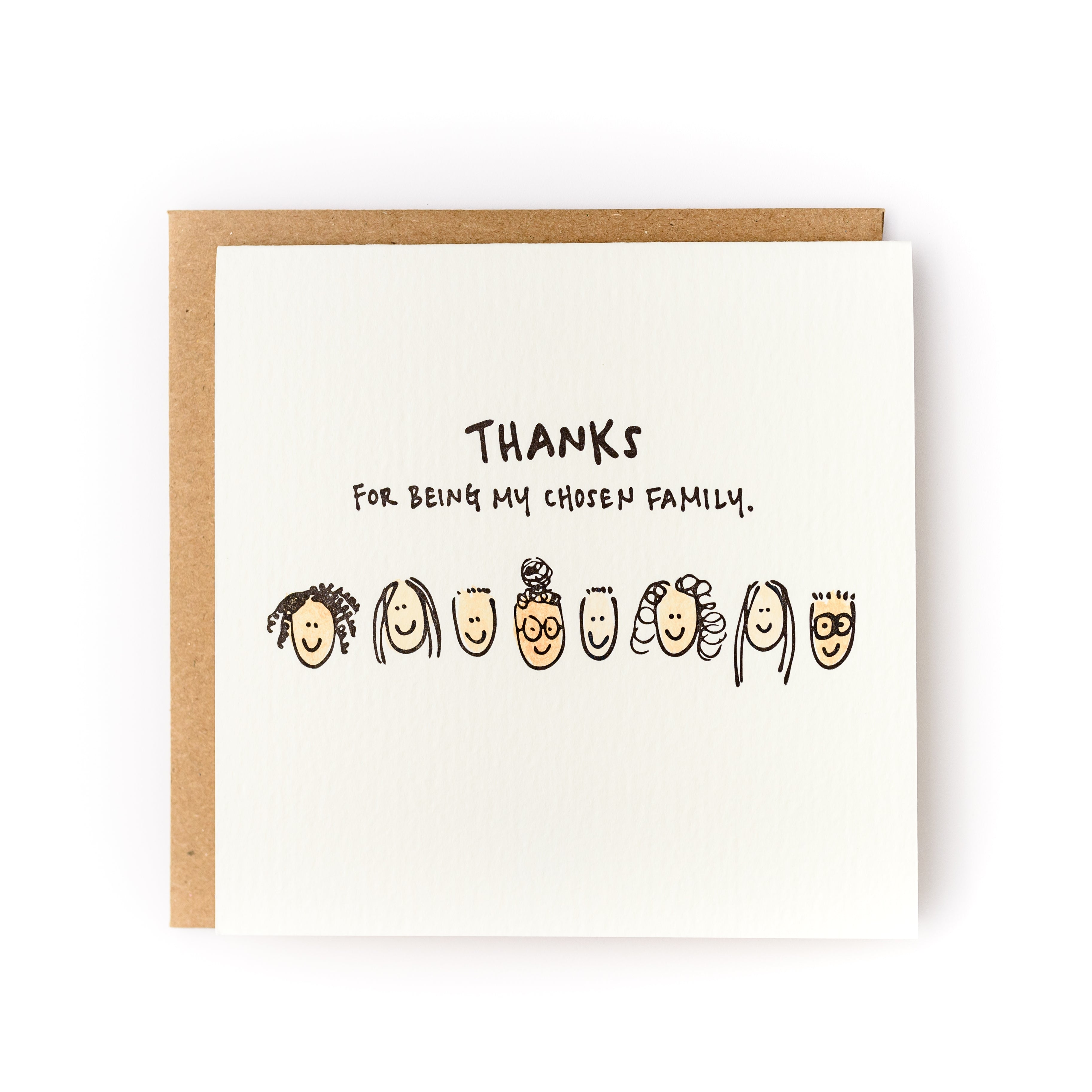 Square white card with black text saying, "Thanks For Being My Chosen Family". Images of several types of people's faces across center of card. A brown envelope is included.
