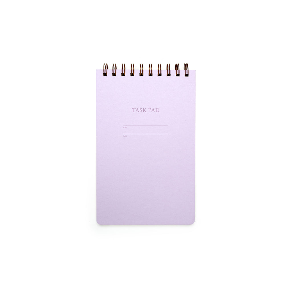 Image of lilac cover with letter pressed text says, “Task pad”. “Name” and “Date” with lines for writing. Coiled binding on top.