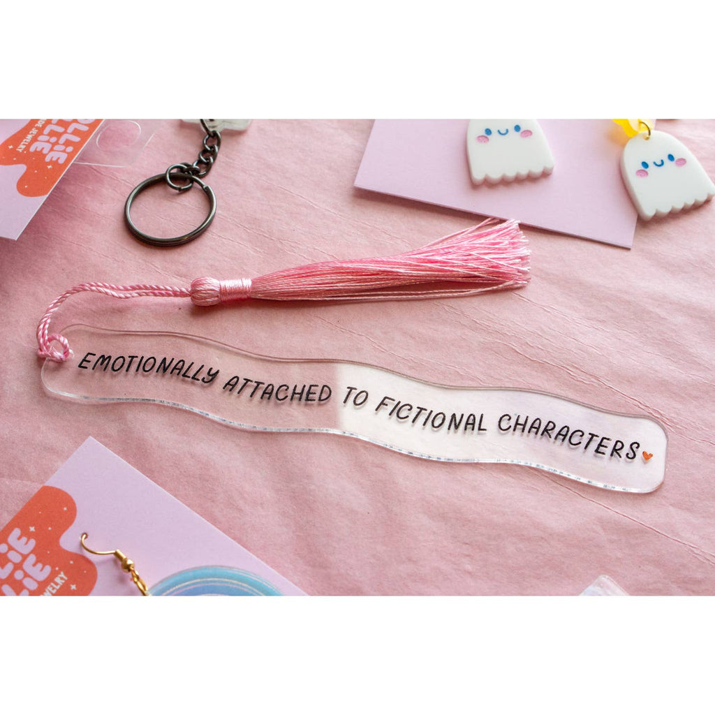 Clear acrylic bookmark with black text says “Emotionally Attached to Fictional Characters” with a small pink heart and a pink tassell.  